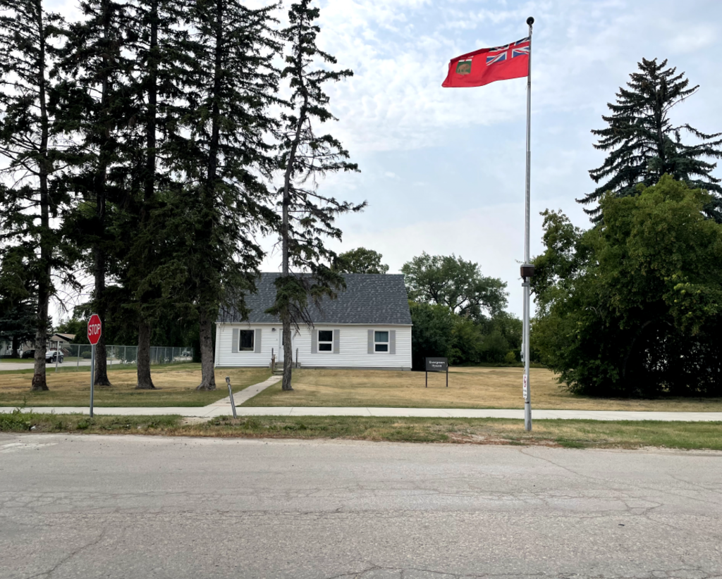 A cottage at the Manitoba Developmental centre. A Manitoba flag flies beside it.